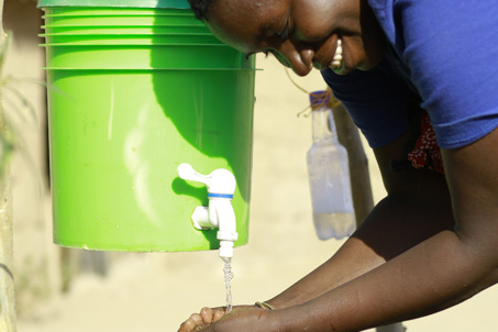 Maria washing her hands using a bucket