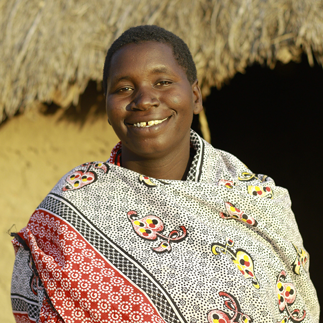 Maria standing outside of her home in Tanzania