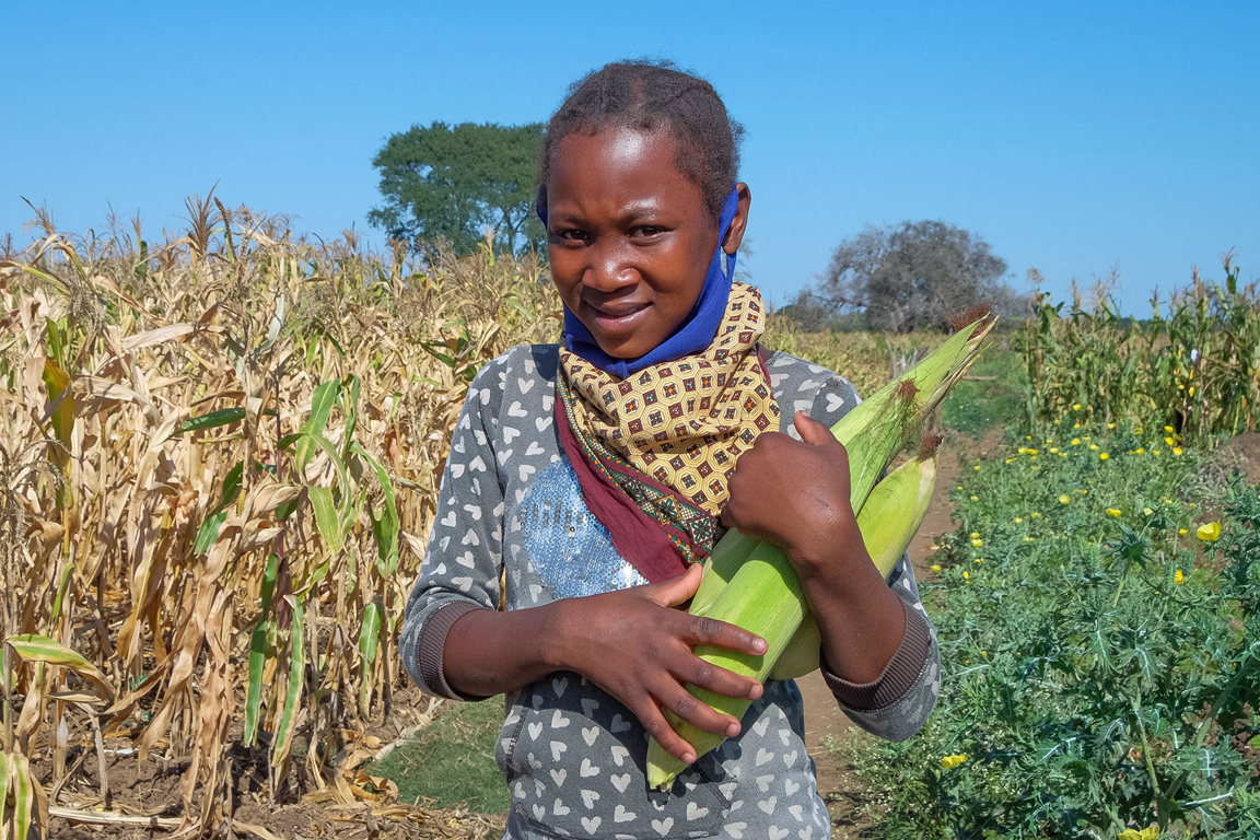 Anatercia carries corn next to her fields in Mozambique