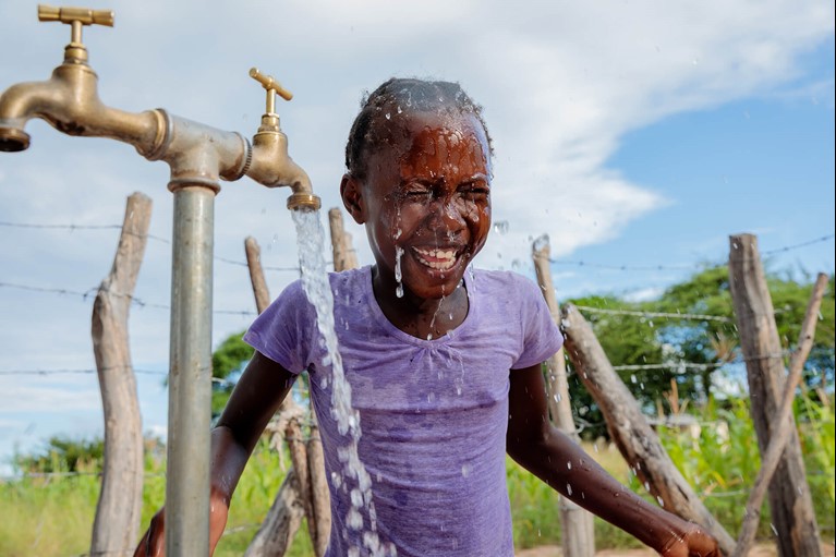 Thandolwayo (9) washes her face from the new water pipe. In June 2017, Caritas Hwange, a Caritas Australia partner, installed a solar powered piped water system in Msuna Hills bringing fresh clean drinking water to the population for the first time. Photo: Richard Wainwright/Caritas Australia.