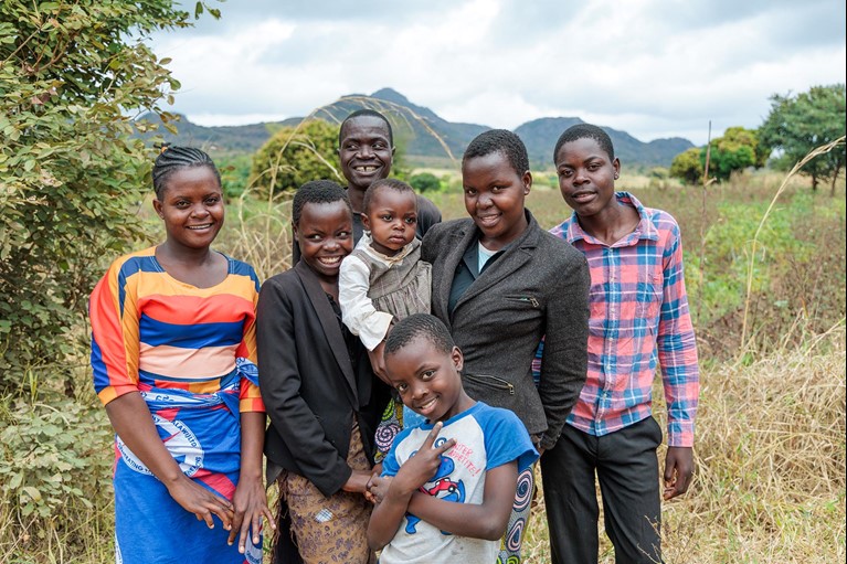 Memory with her siblings and father near their home in Malawi. Photo: Tim Lam/Caritas Australia