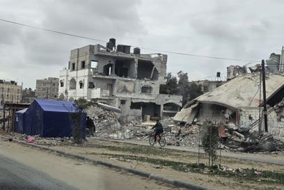 People Cycle Past Destroyed Buildings In Gaza Photo Credit CRS