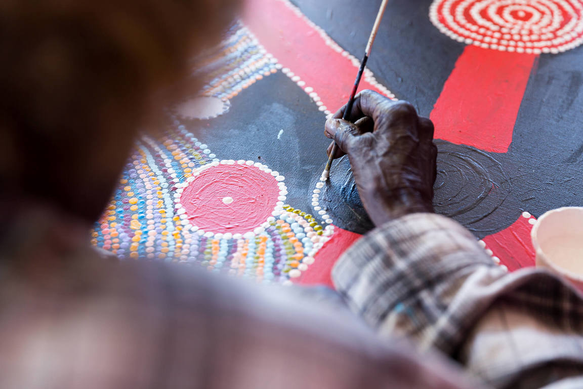 Woman painting traditional Australian Indigenous artwork